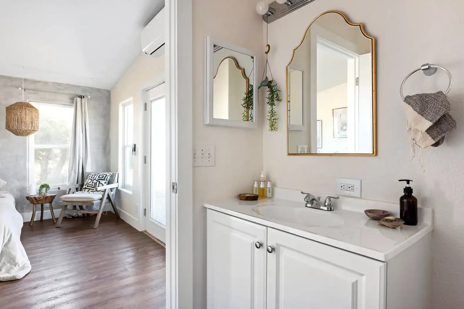 Bright bathroom with a stylish mirror and modern sink adjacent to a cozy bedroom