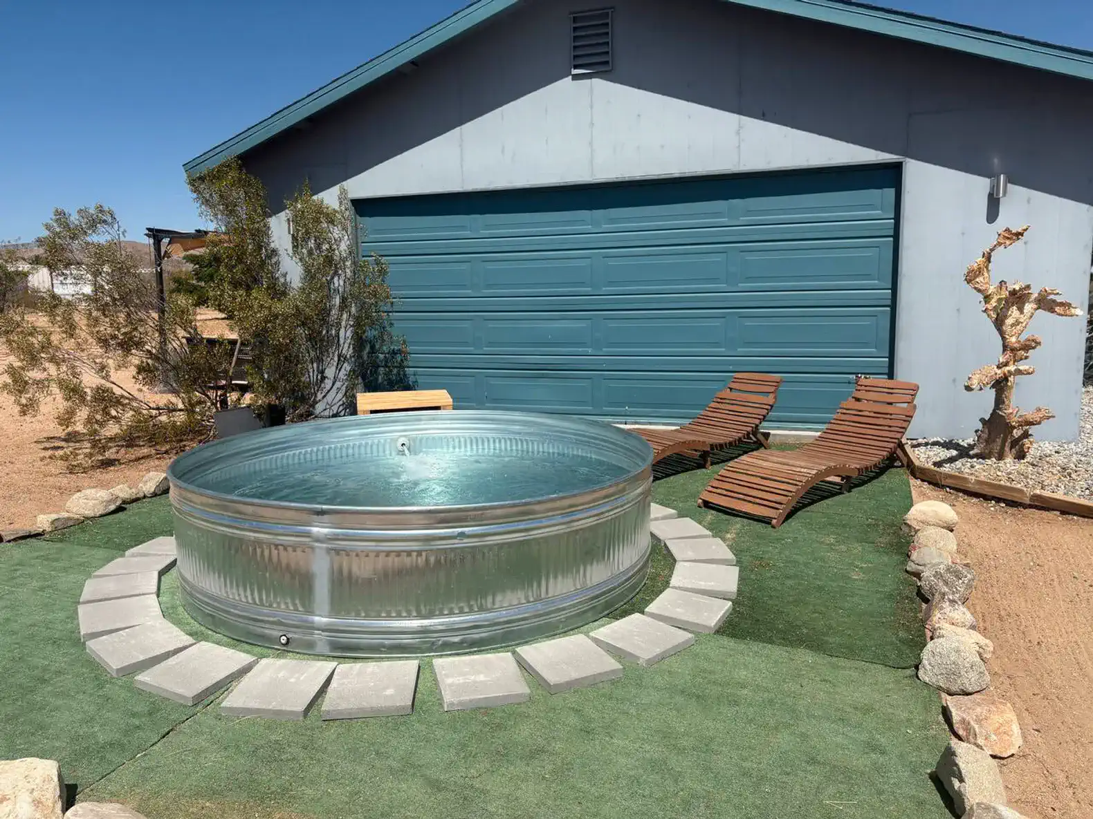 Outdoor area featuring a circular hot tub and lounge chairs on green turf