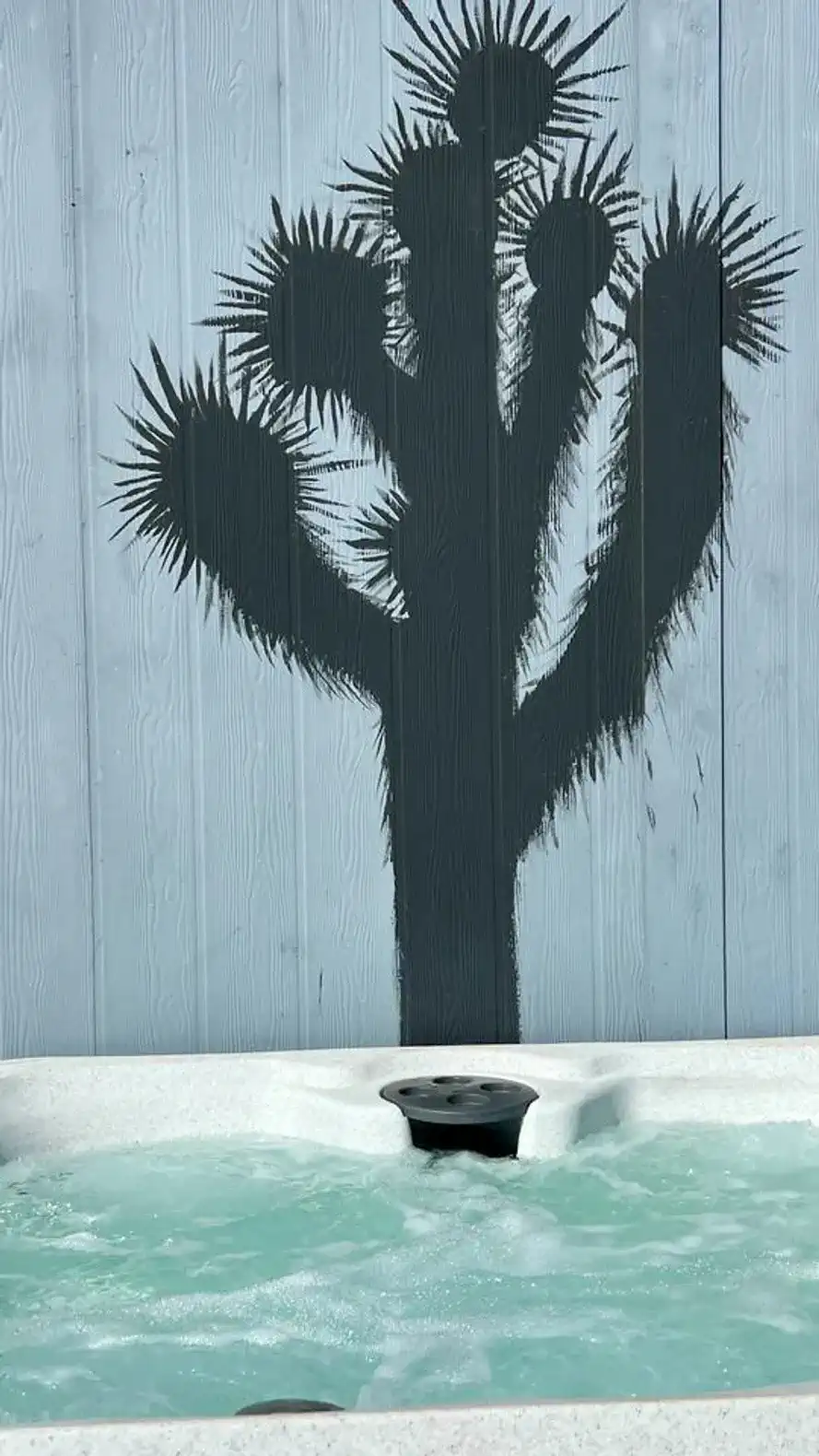 Hot tub with a unique cactus mural on the wall behind it