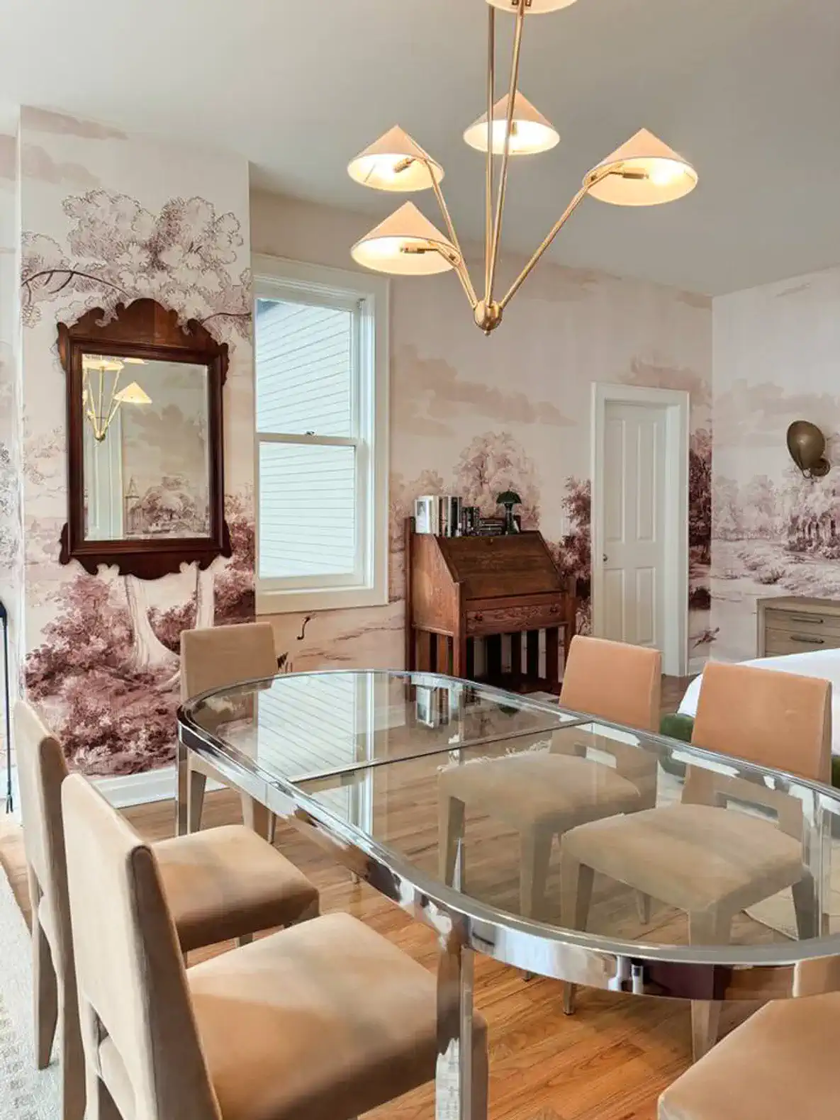 Elegant dining area with a glass table and stylish chairs, featuring scenic wallpaper