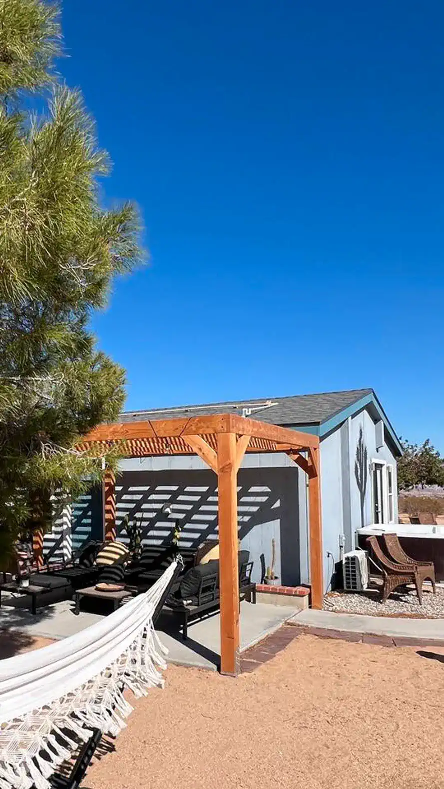 Outdoor seating area with pergola and hammock under a clear blue sky