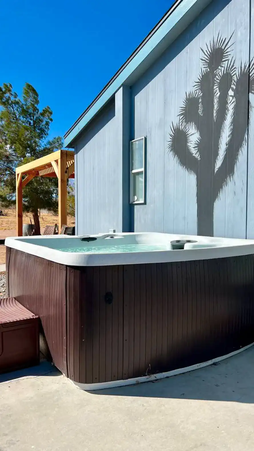 Hot tub surrounded by desert landscape and a shadow of a Joshua tree