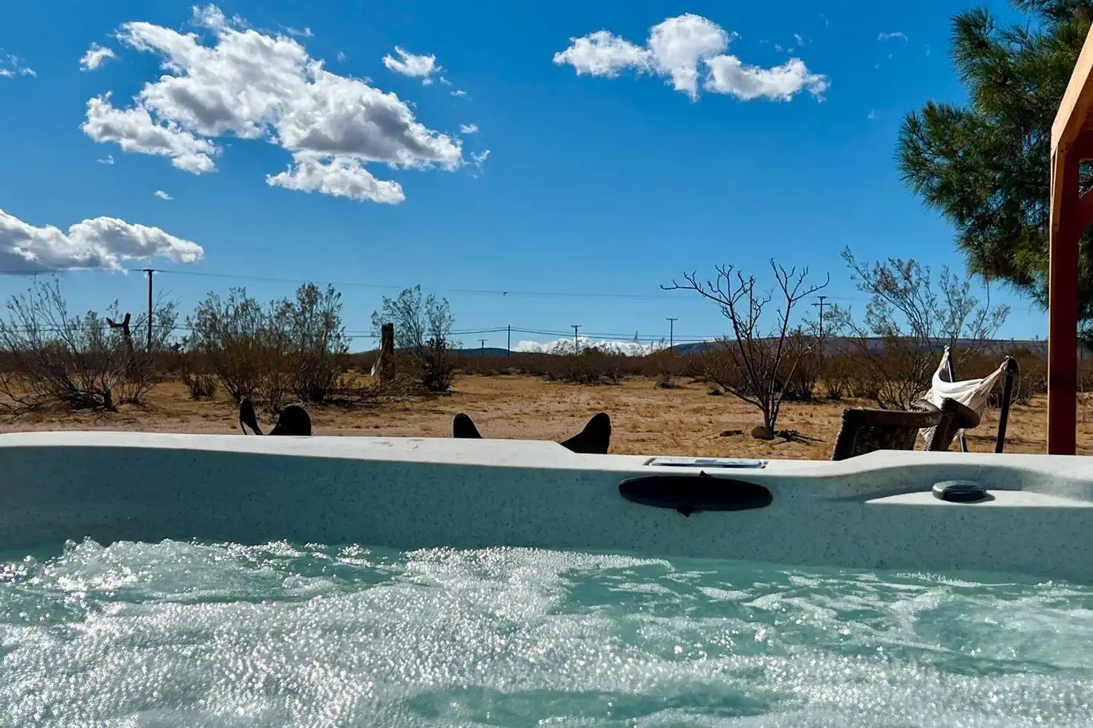 Hot tub with bubbling water overlooking a desert landscape and blue sky