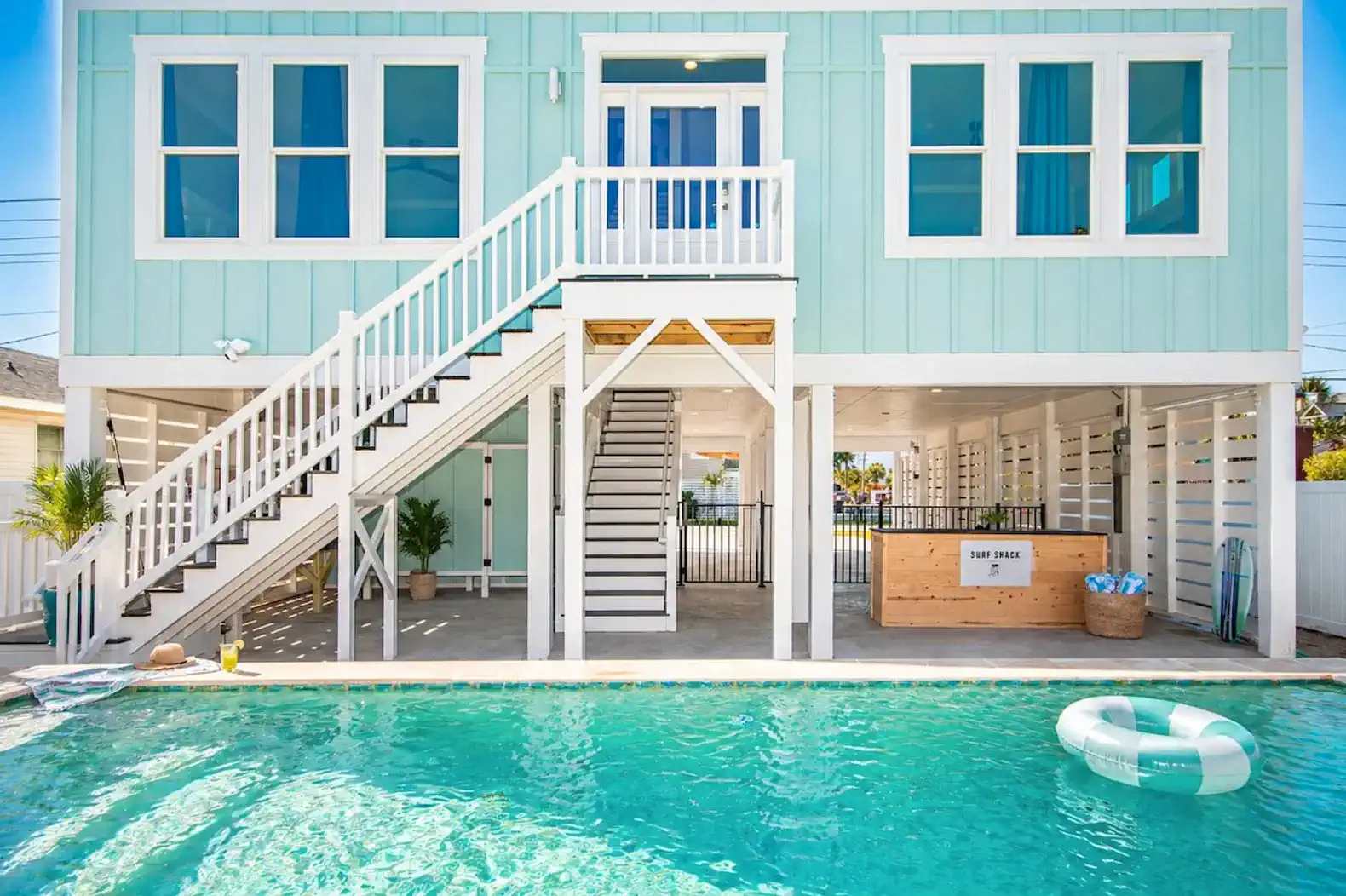 Bright blue house with a pool and stairs leading to the upper level