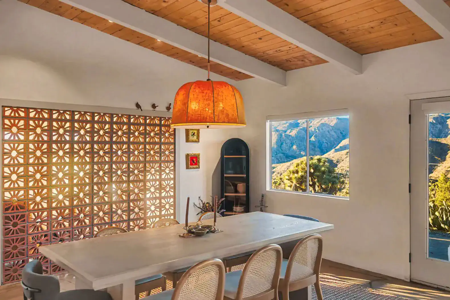 Bright dining area with a large table and unique pendant light overlooking desert views