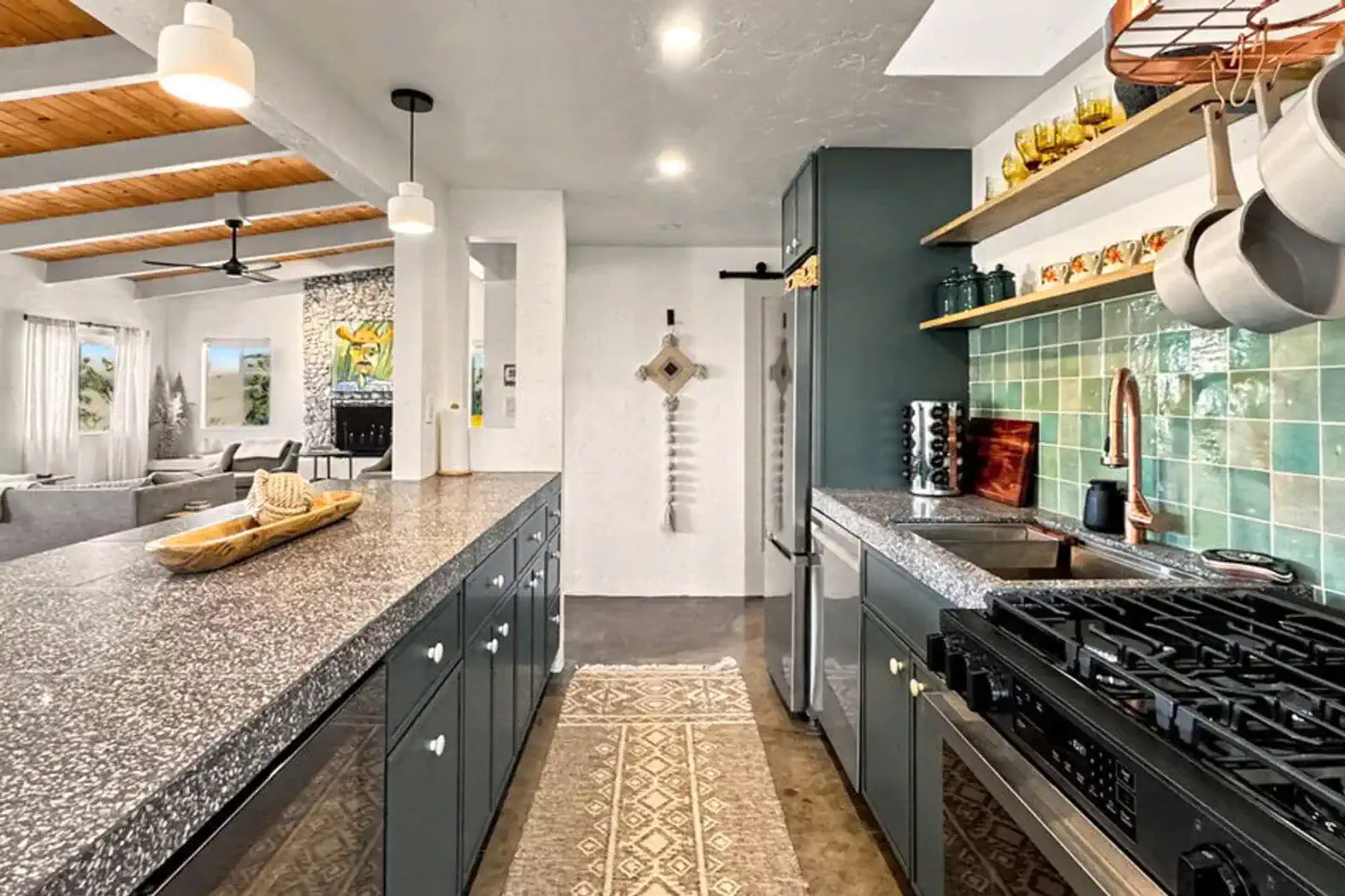 Modern kitchen with granite countertops, teal backsplash, and open shelving