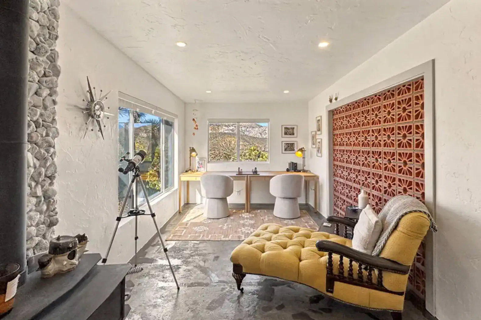 Cozy workspace with a yellow chaise lounge, large windows, and a telescope for scenic views