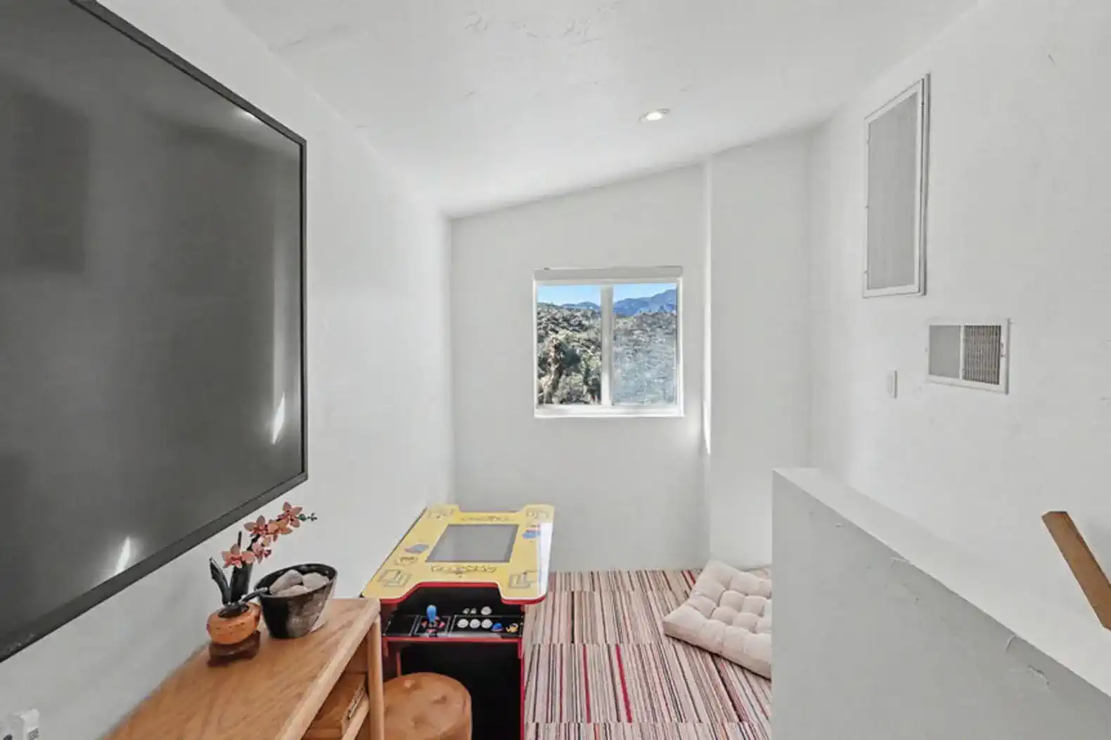 Cozy nook with a large TV, game table, and mountain views through the window