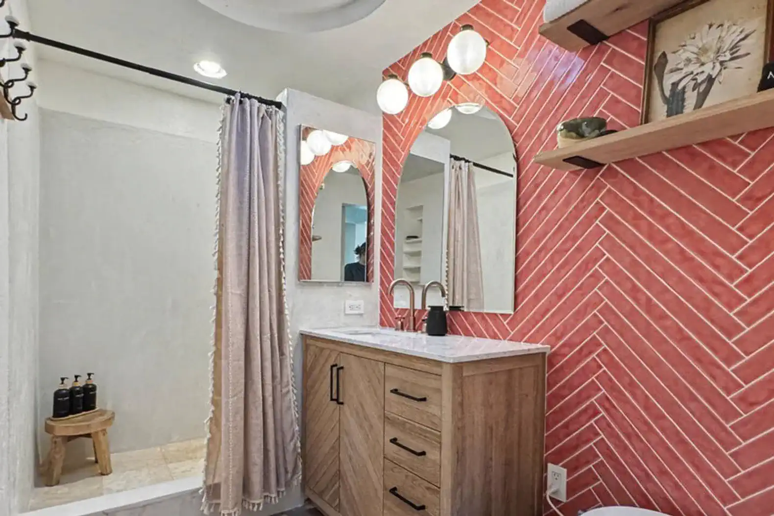 Stylish bathroom featuring a wooden vanity, red herringbone tile wall, and modern lighting