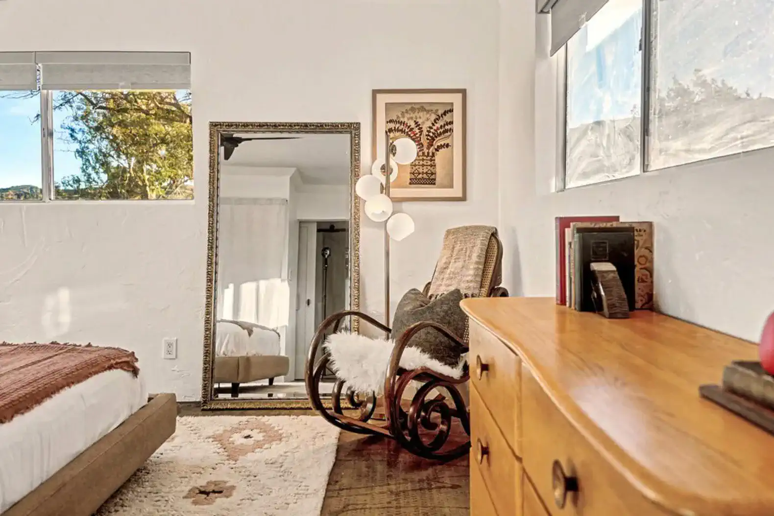 Cozy bedroom with a rocking chair, mirror, and wooden dresser