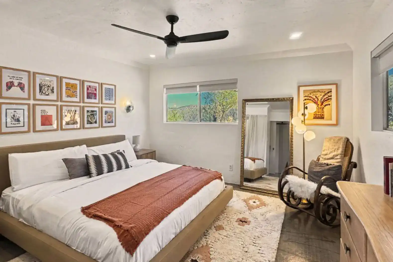 Spacious master bedroom with a large bed, artwork on the walls, and natural light from windows