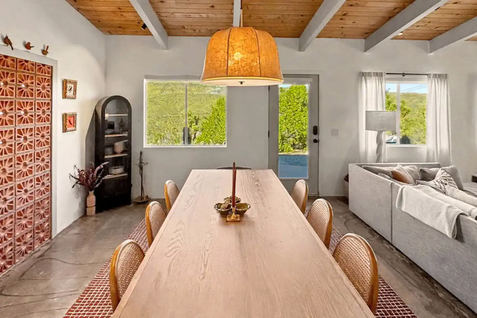 Spacious dining area with a long wooden table and natural light from large windows