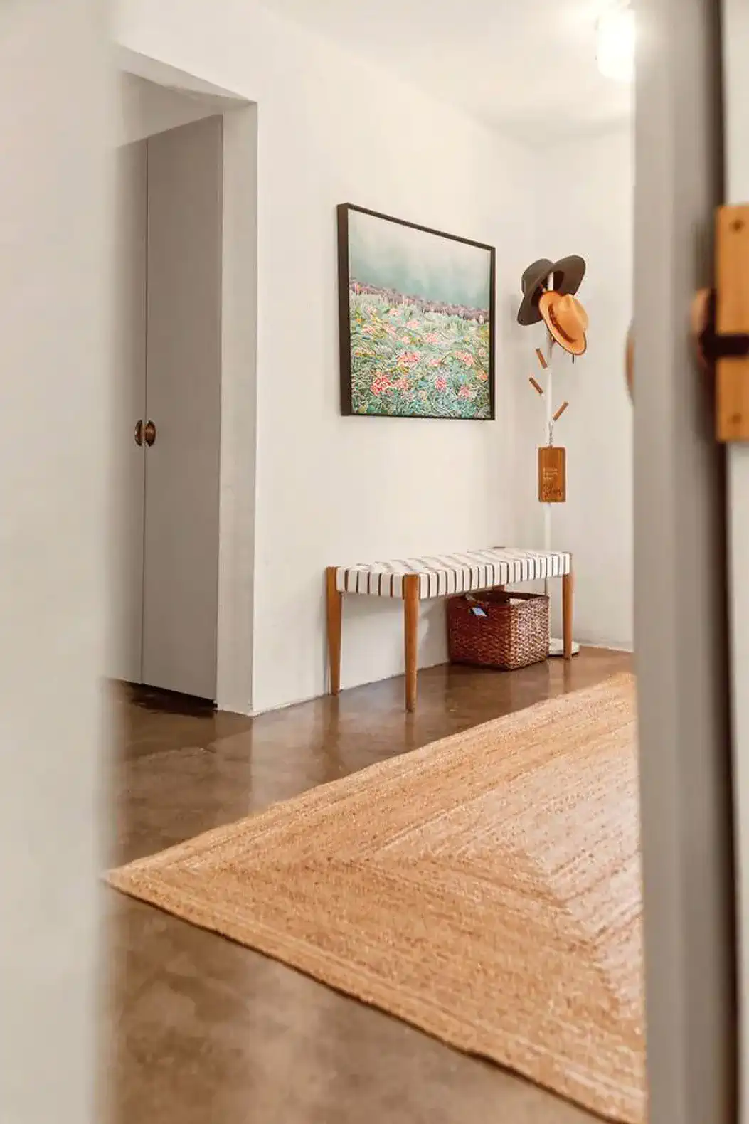 Welcoming entrance with a bench, artwork, and decorative hats