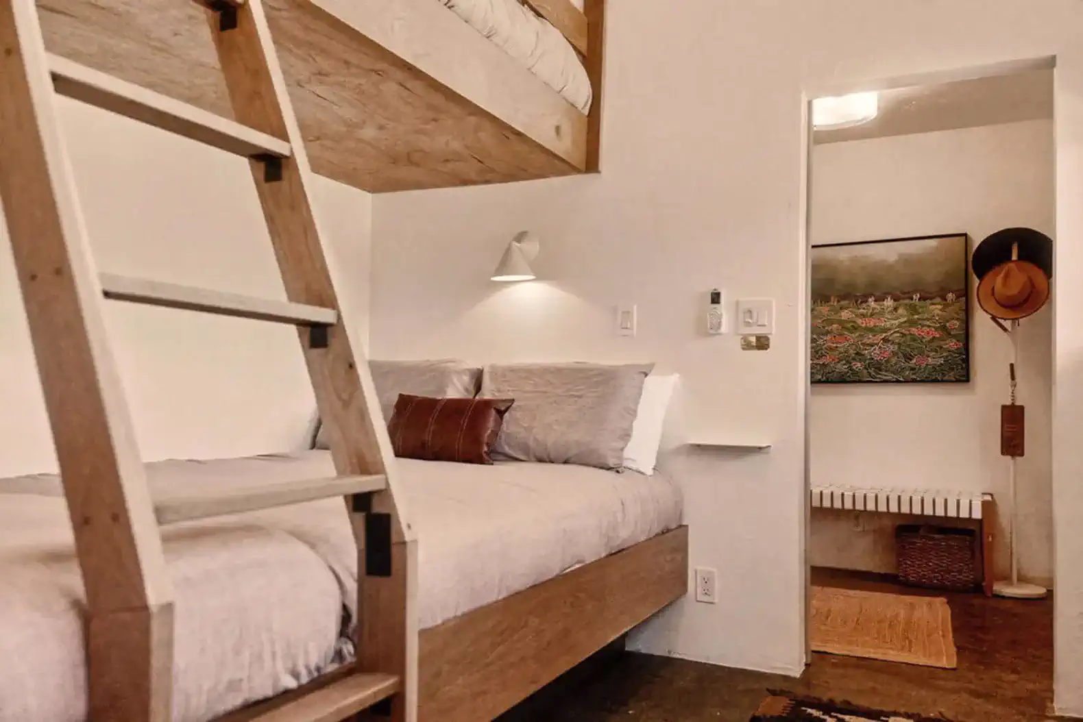 Cozy guest bedroom with a bunk bed and a single bed, featuring warm lighting and rustic decor