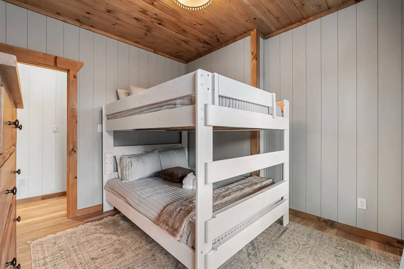 Cozy bunk room with white wooden bunk beds and warm wooden accents