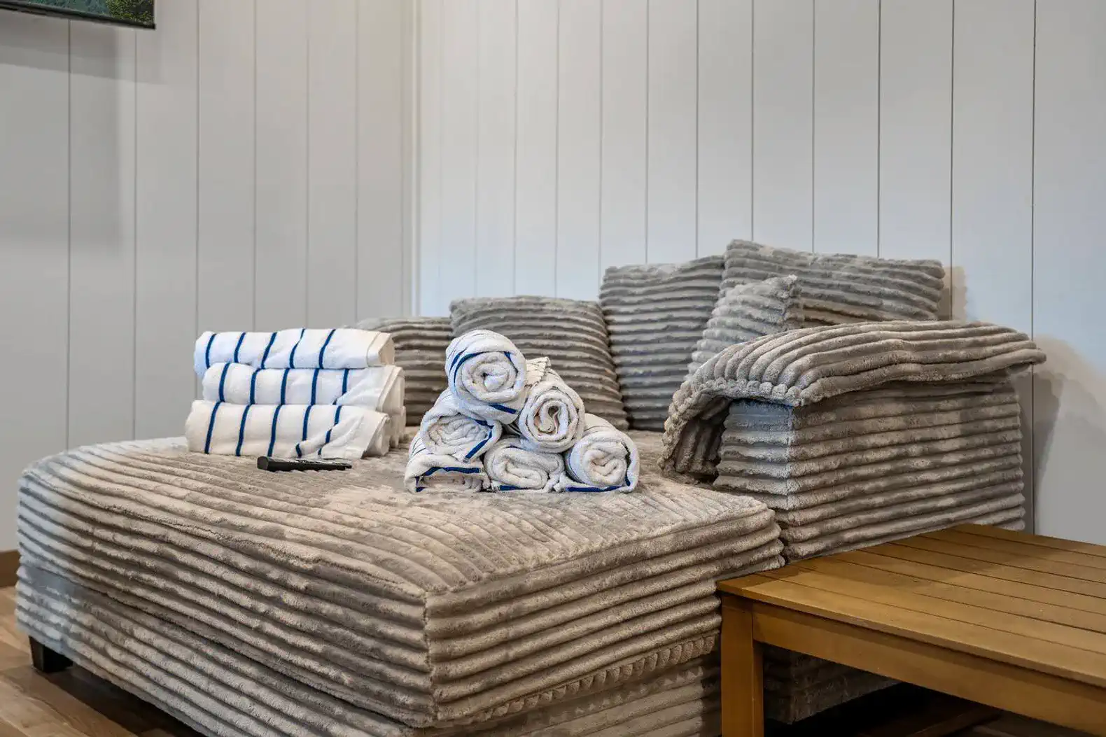 Cozy seating area with plush gray couch and neatly stacked towels