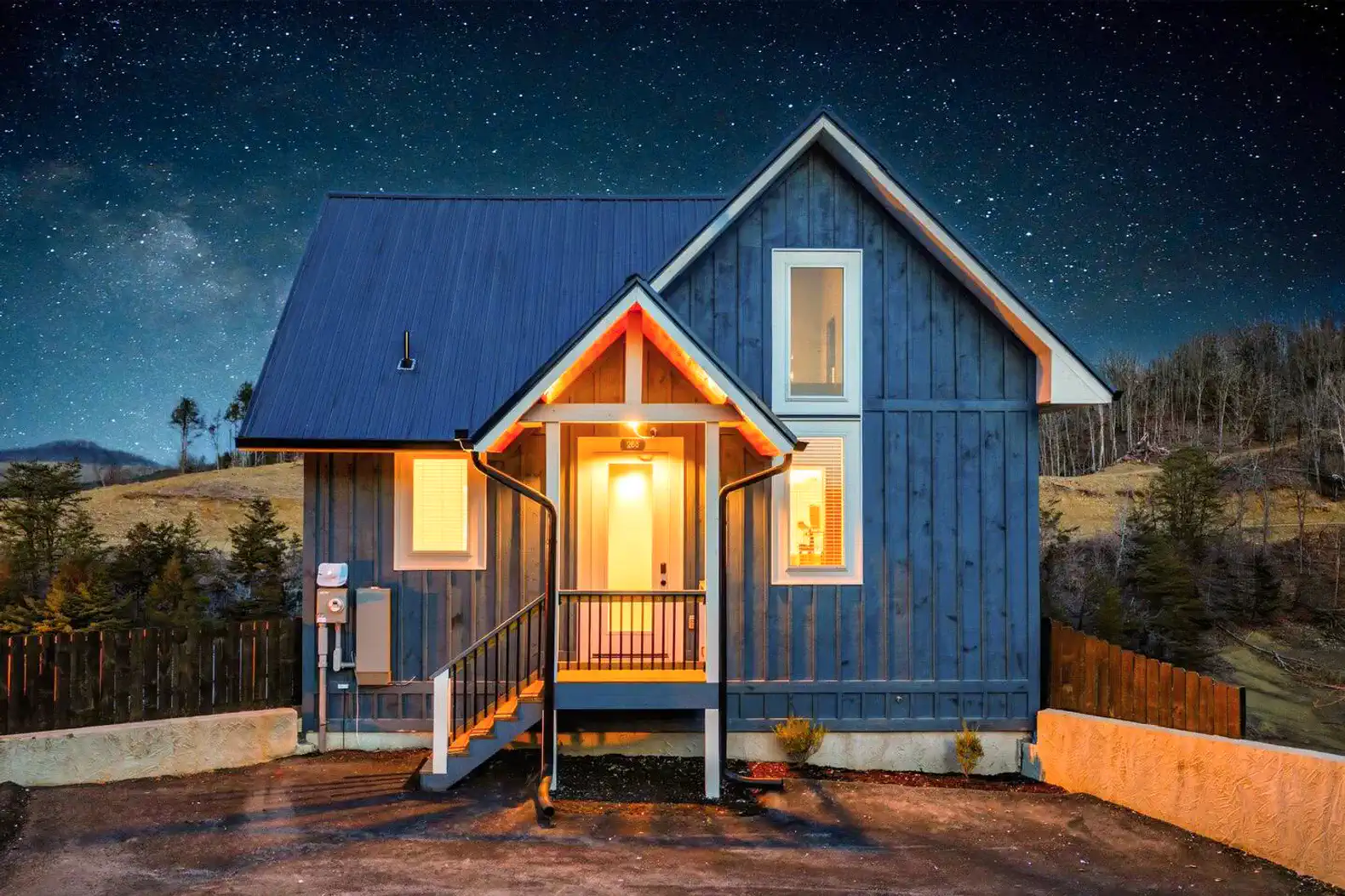 Charming blue cabin exterior with illuminated entrance and starry night sky