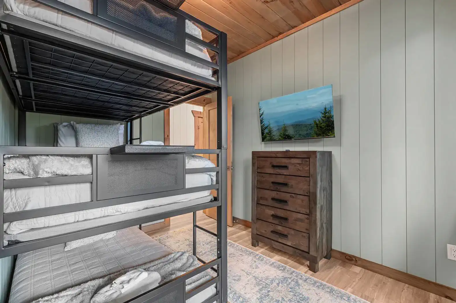 Bunk room featuring a metal bunk bed and a dresser with a TV on the wall