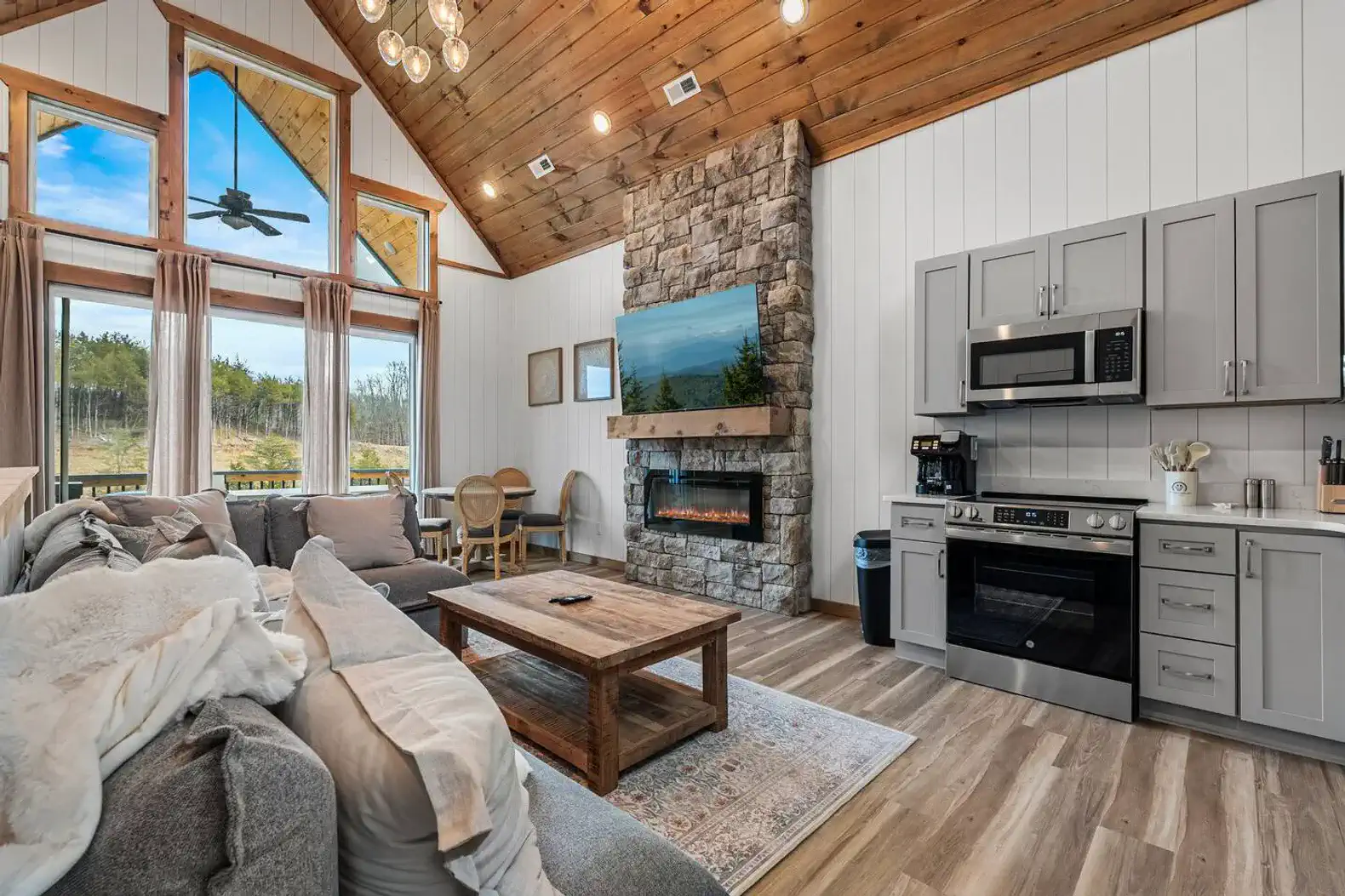 Cozy living room with stone fireplace and large windows overlooking nature