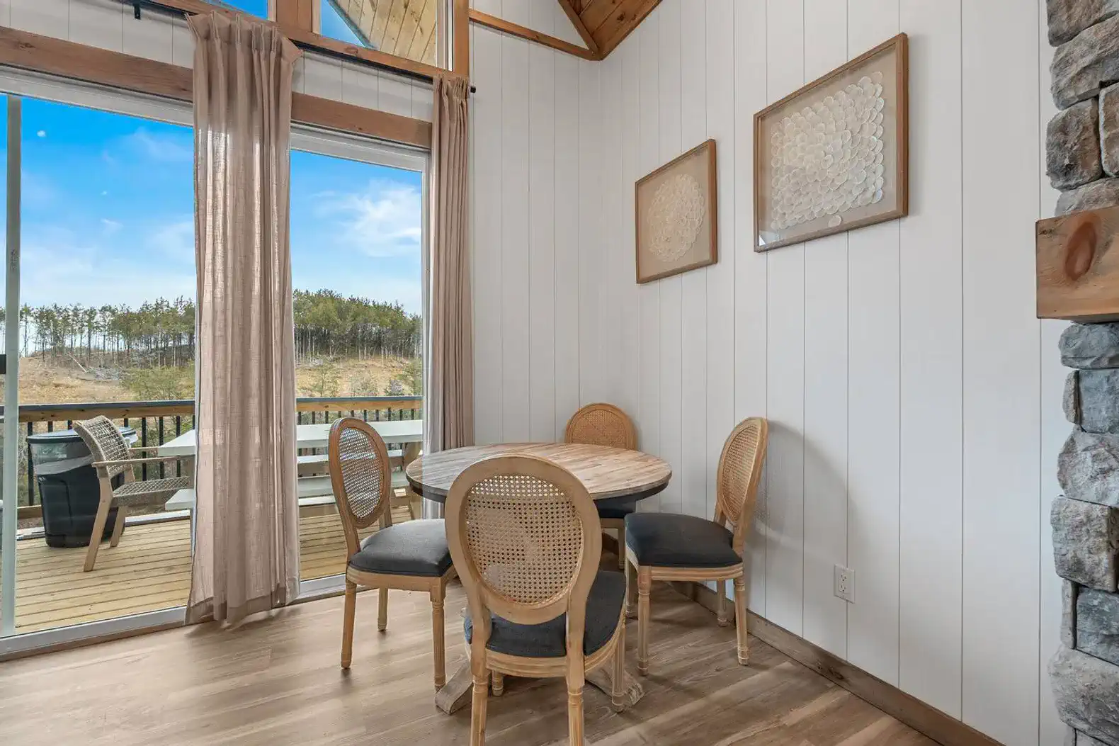 Cozy dining area with round table and four chairs near large windows overlooking the lake