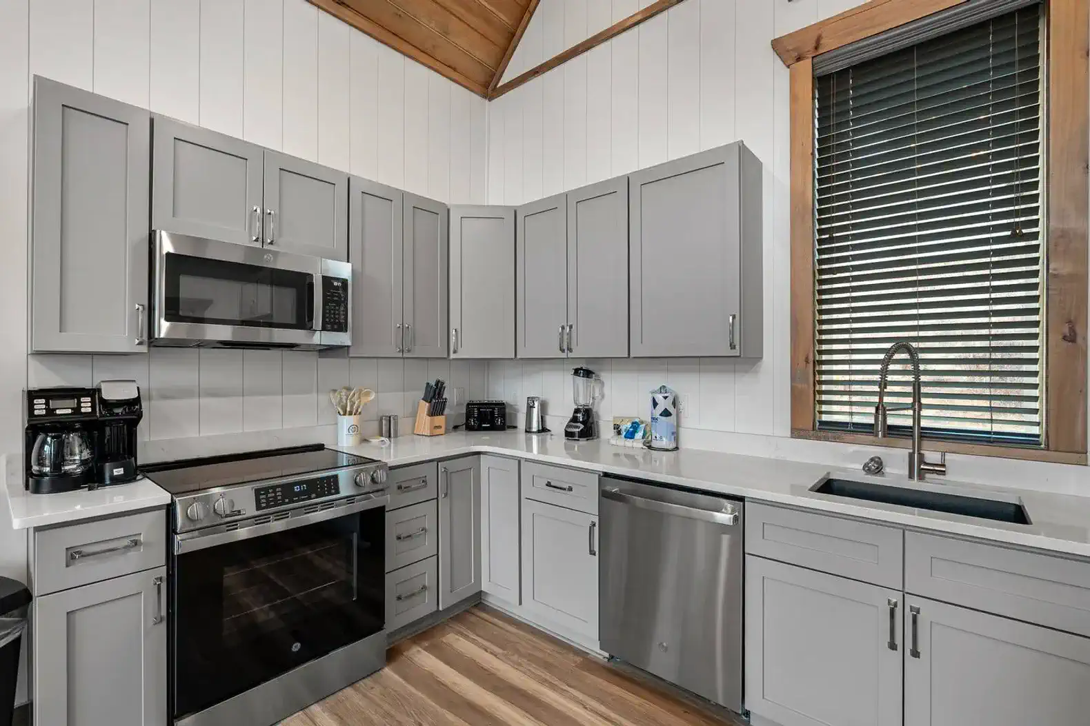Modern kitchen with gray cabinets, stainless steel appliances, and a large window