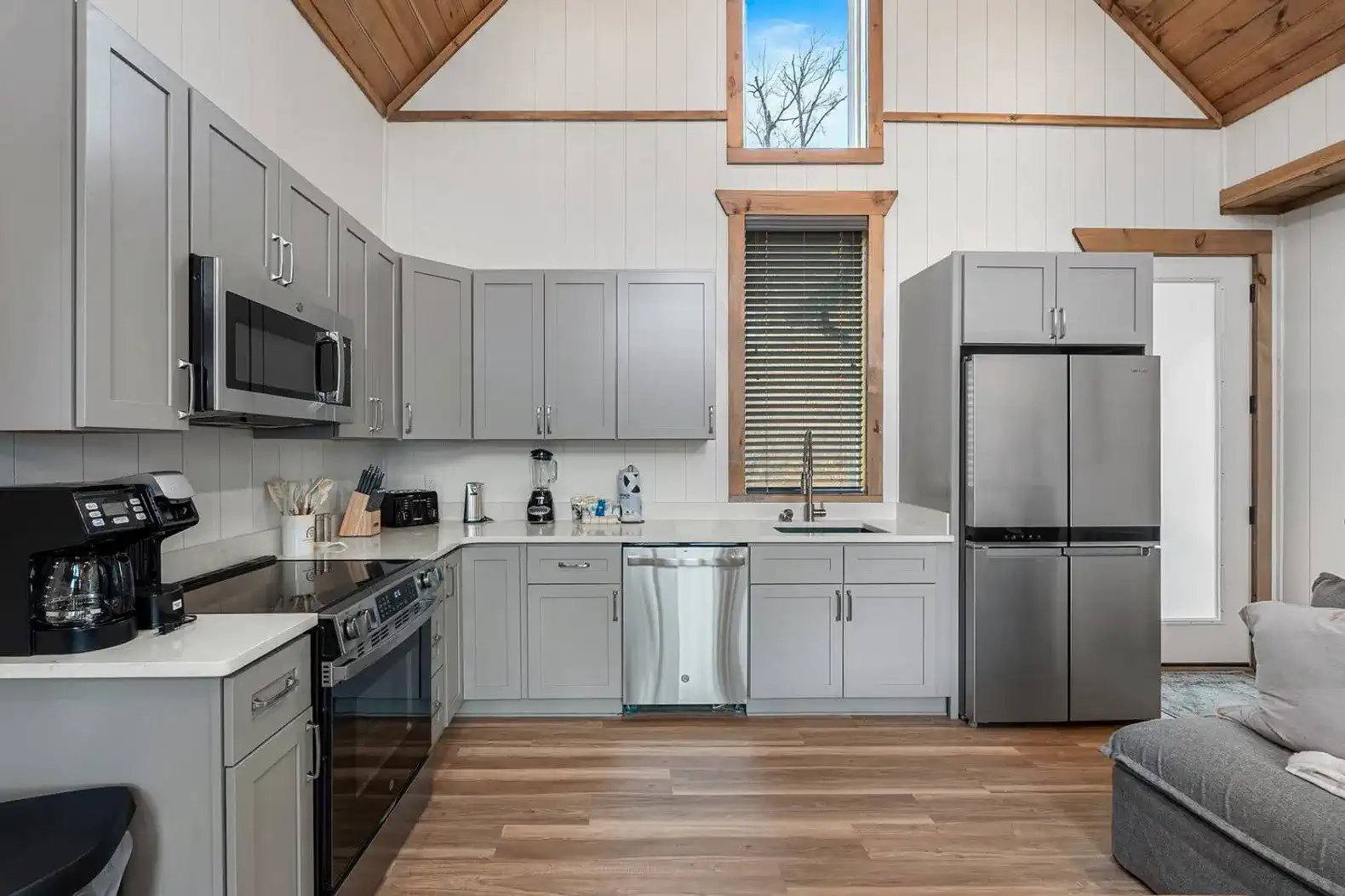 Modern kitchen with gray cabinets, stainless steel appliances, and a cozy seating area