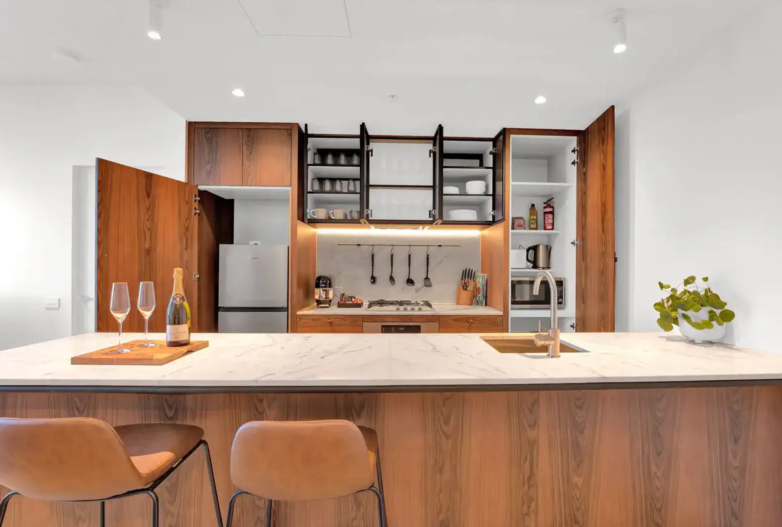 Modern kitchen with marble island, wooden cabinetry, and stainless steel appliances