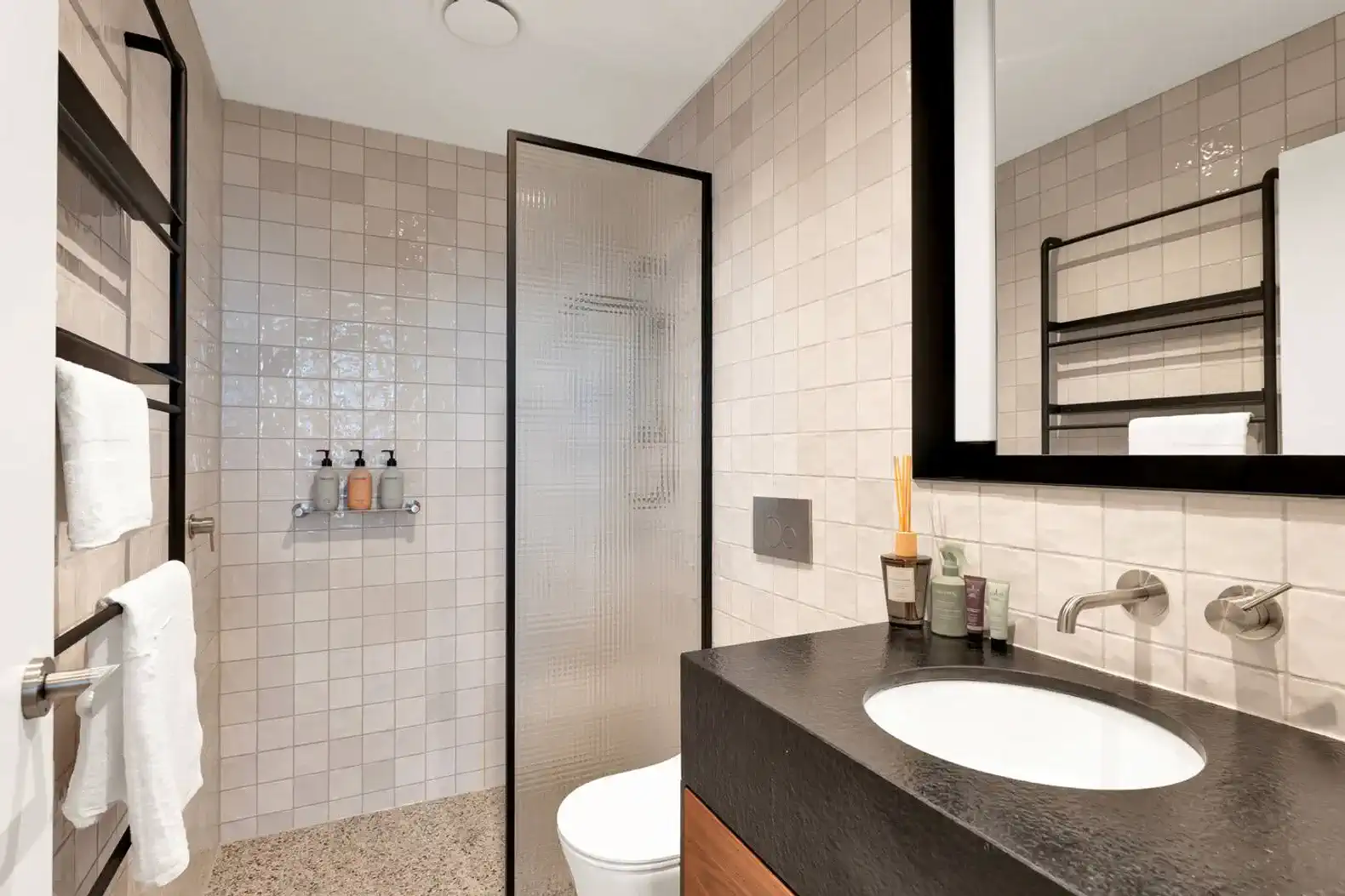 Modern bathroom with tiled walls, walk-in shower, and sleek vanity