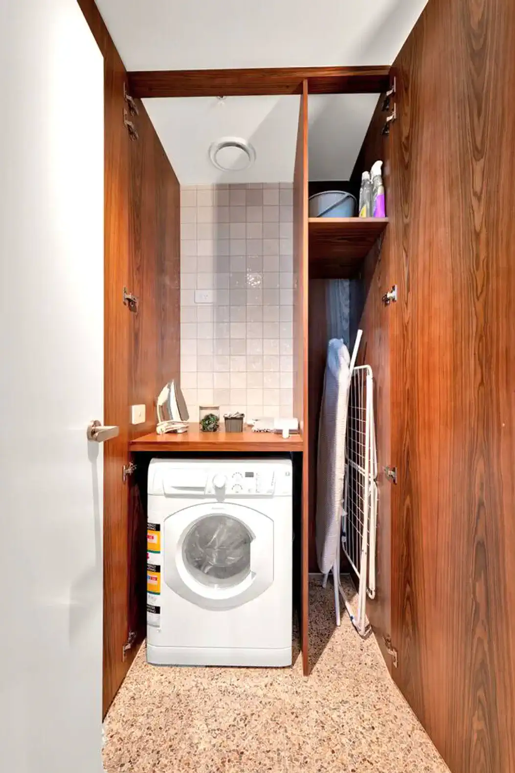 Compact laundry area with washing machine and storage shelves
