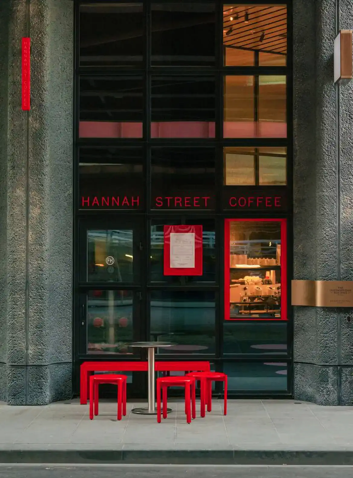 Modern coffee shop entrance with red accents and outdoor seating