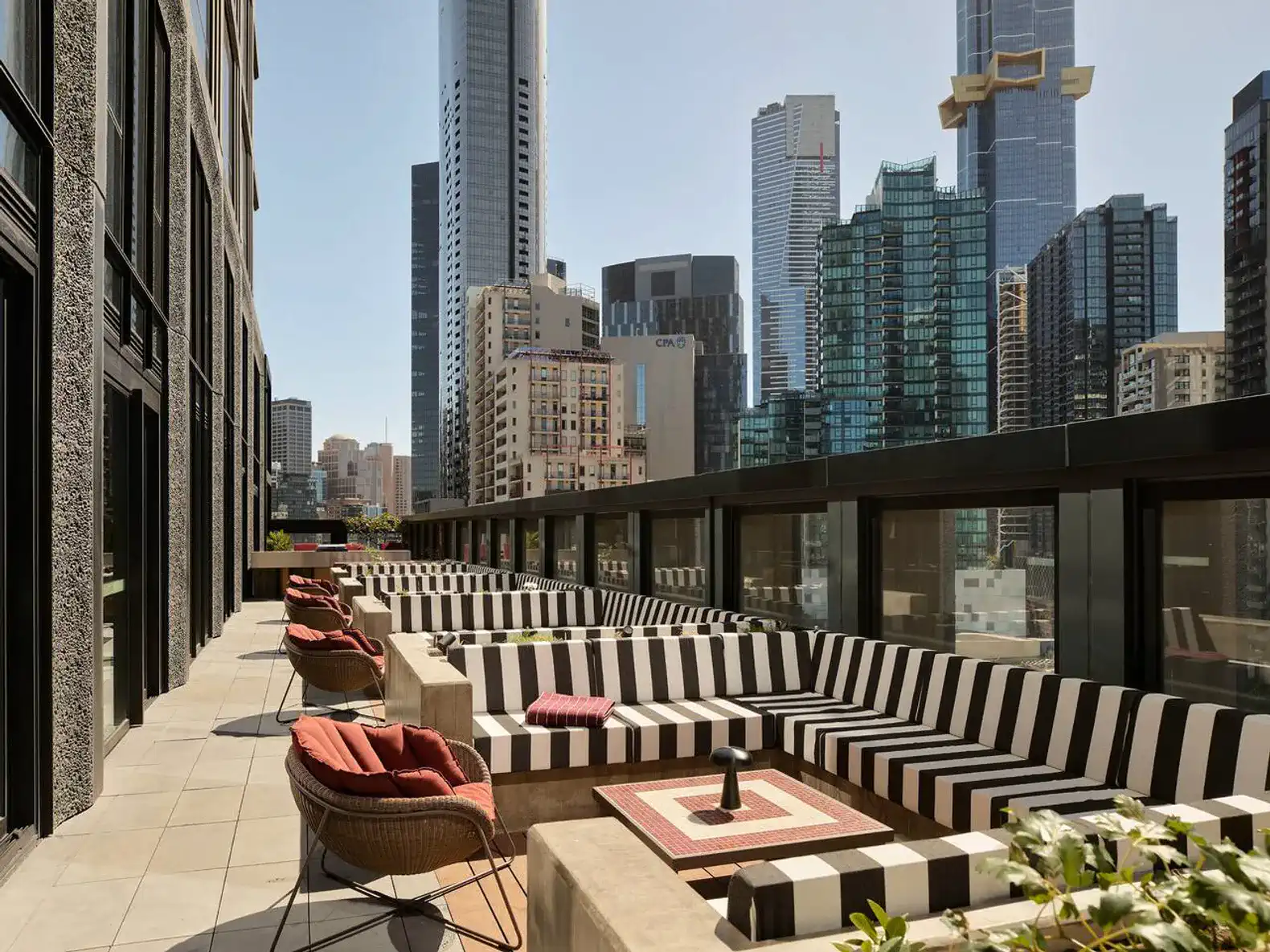 Stylish outdoor seating area with striped couches overlooking a city skyline
