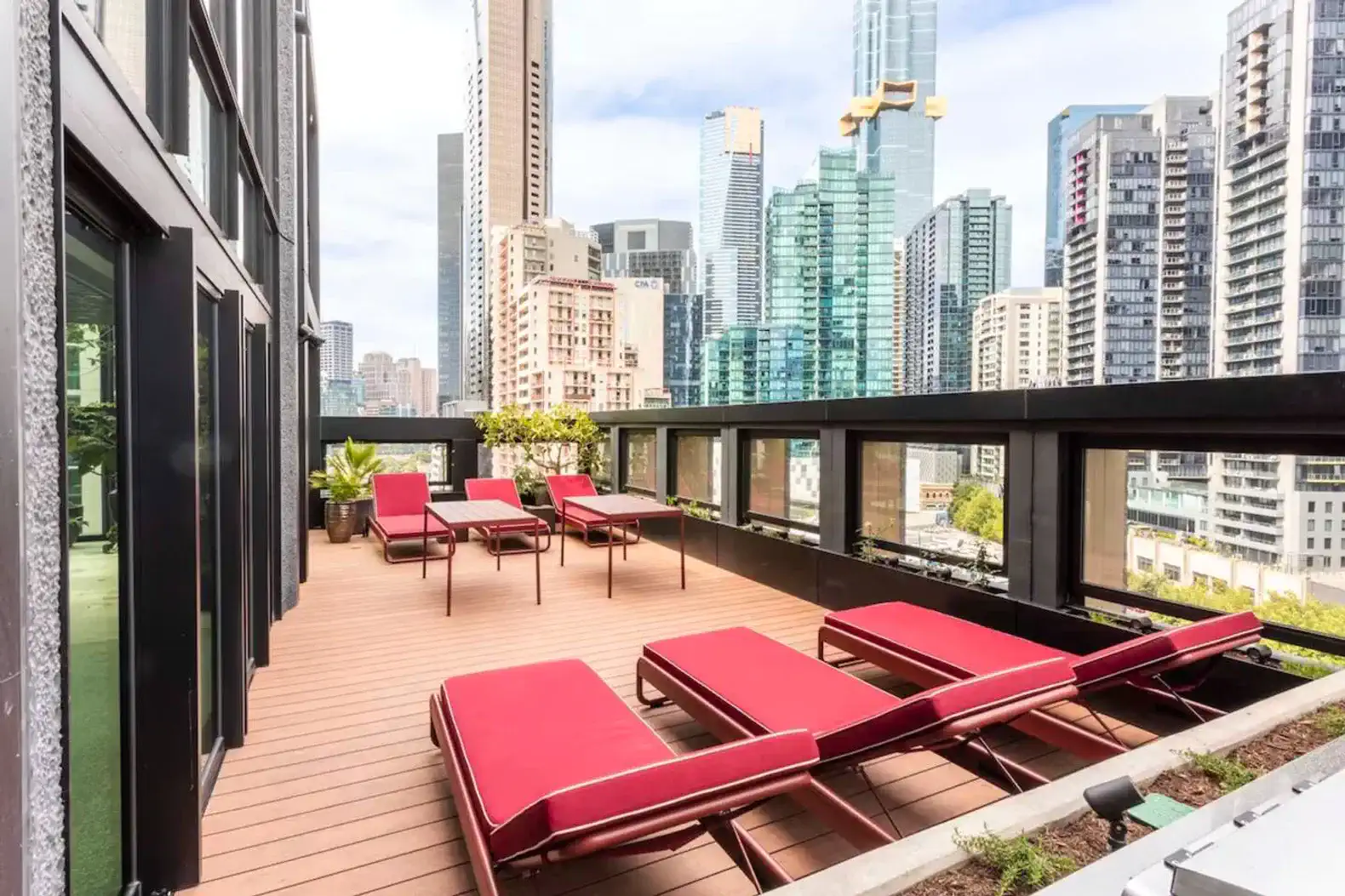 Spacious outdoor terrace with red lounge chairs and city skyline views