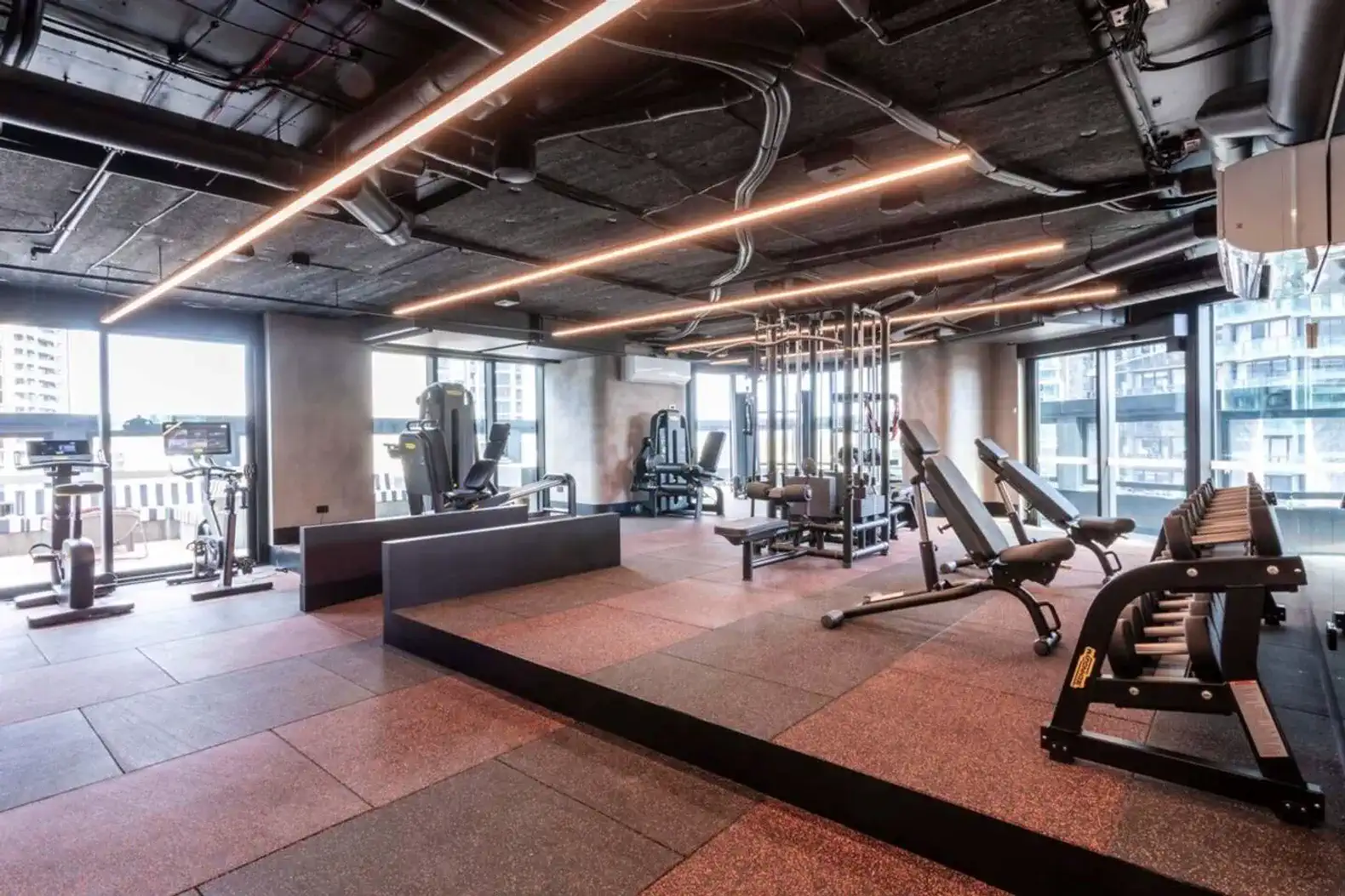 modern gym with various workout equipment and large windows