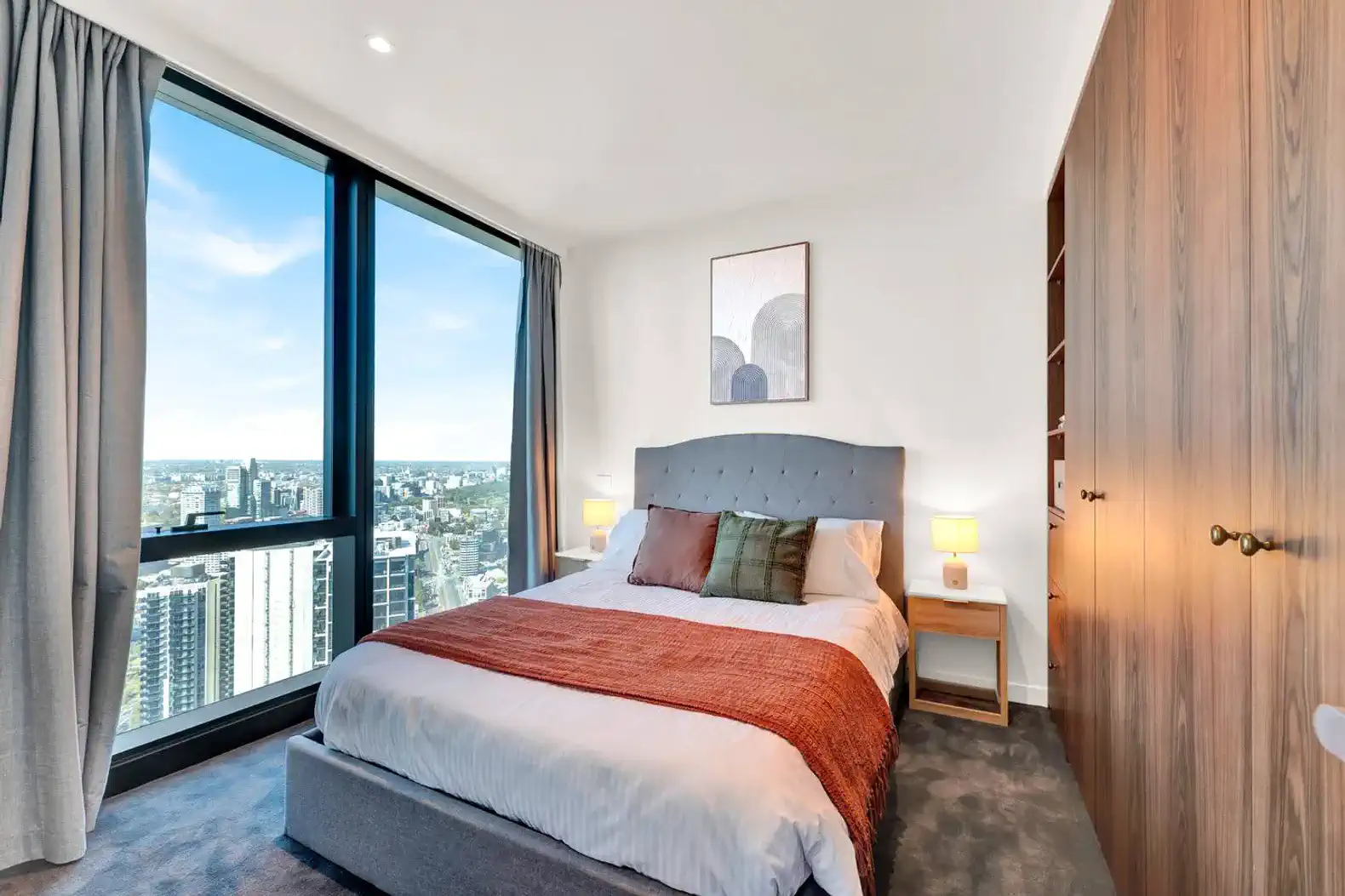 Cozy master bedroom with a large window offering panoramic city views