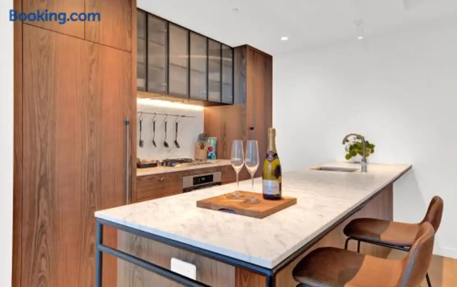 Modern kitchen with marble island, wooden cabinetry, and stylish bar stools