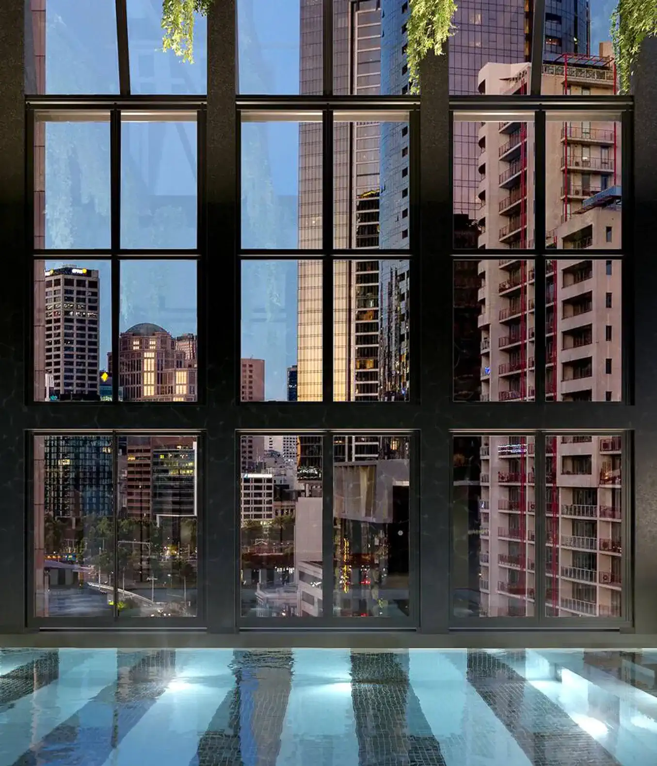 Panoramic city views through large windows overlooking a pool area