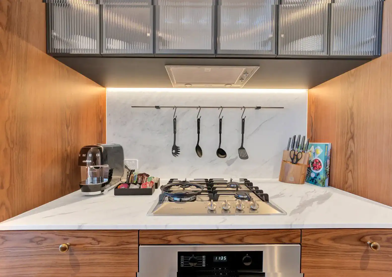 Modern kitchen with marble countertop, gas stove, and hanging utensils