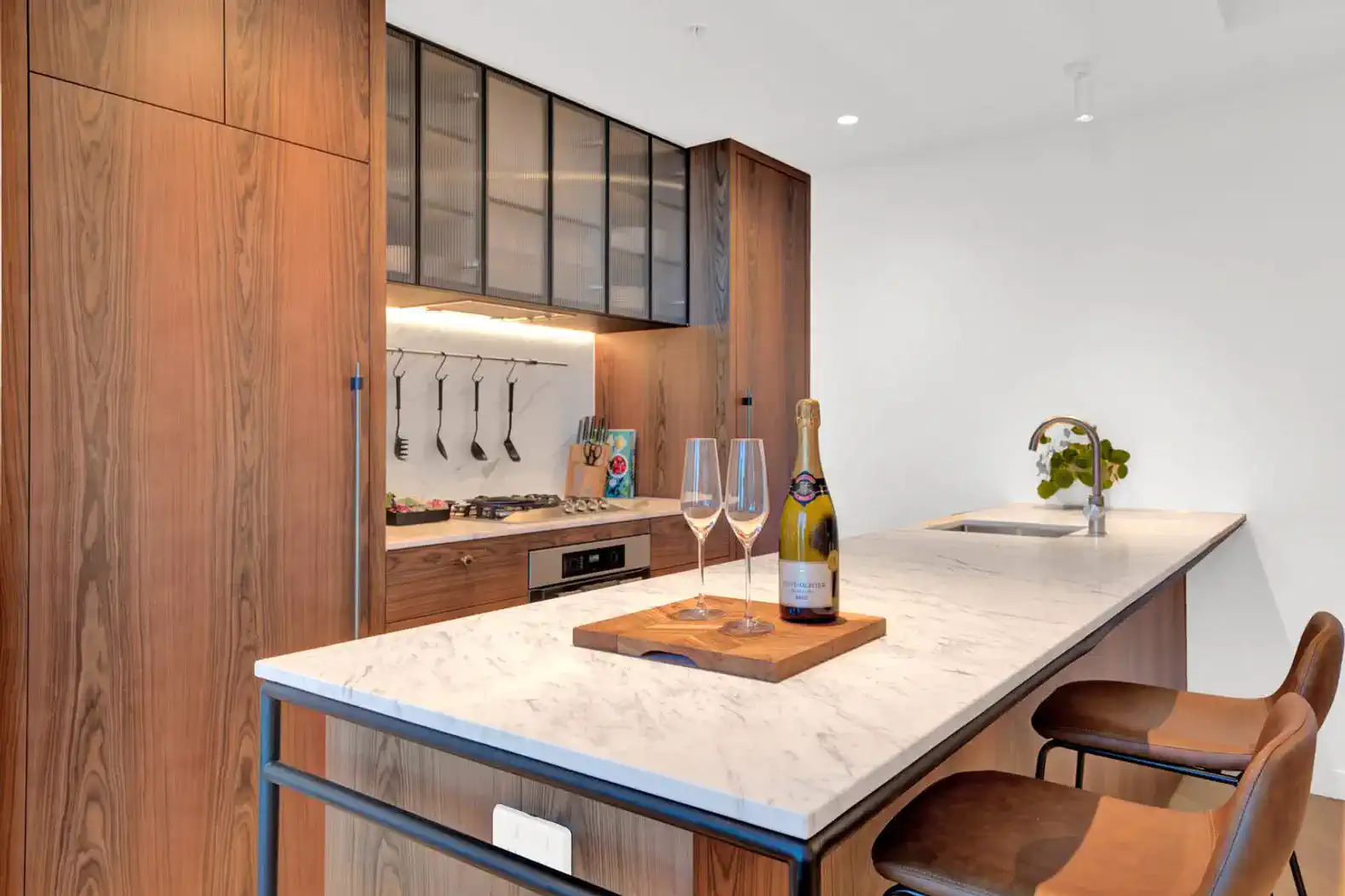 Modern kitchen with marble island, wooden cabinetry, and cooking utensils