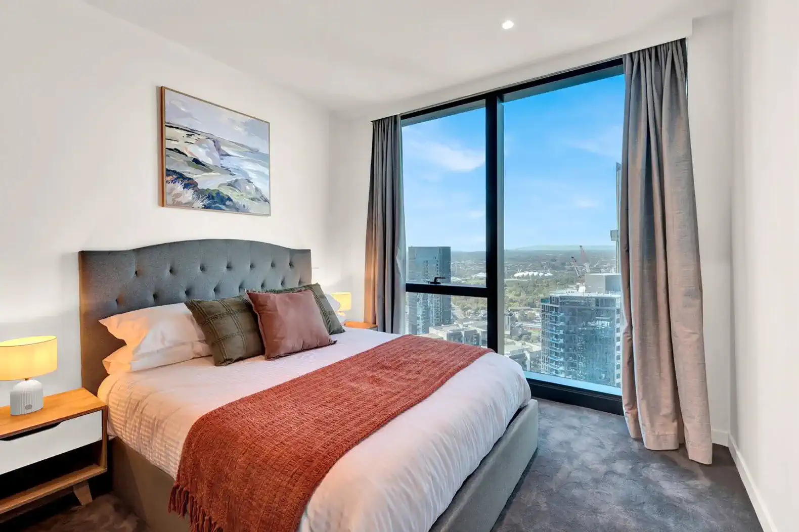 Cozy master bedroom with a large window showcasing panoramic city views