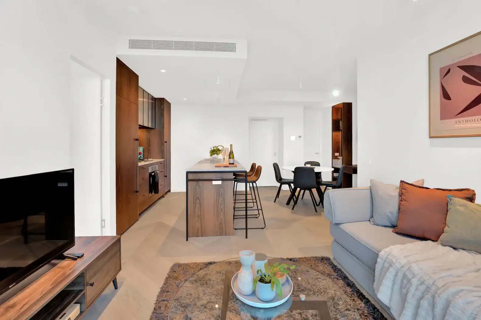 Modern living room with a cozy sofa, stylish decor, and an open kitchen area