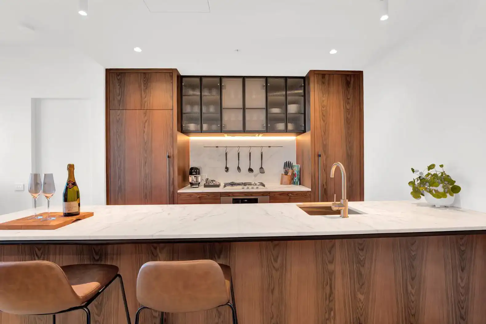 Modern kitchen with wooden cabinetry, marble countertop, and stylish bar stools