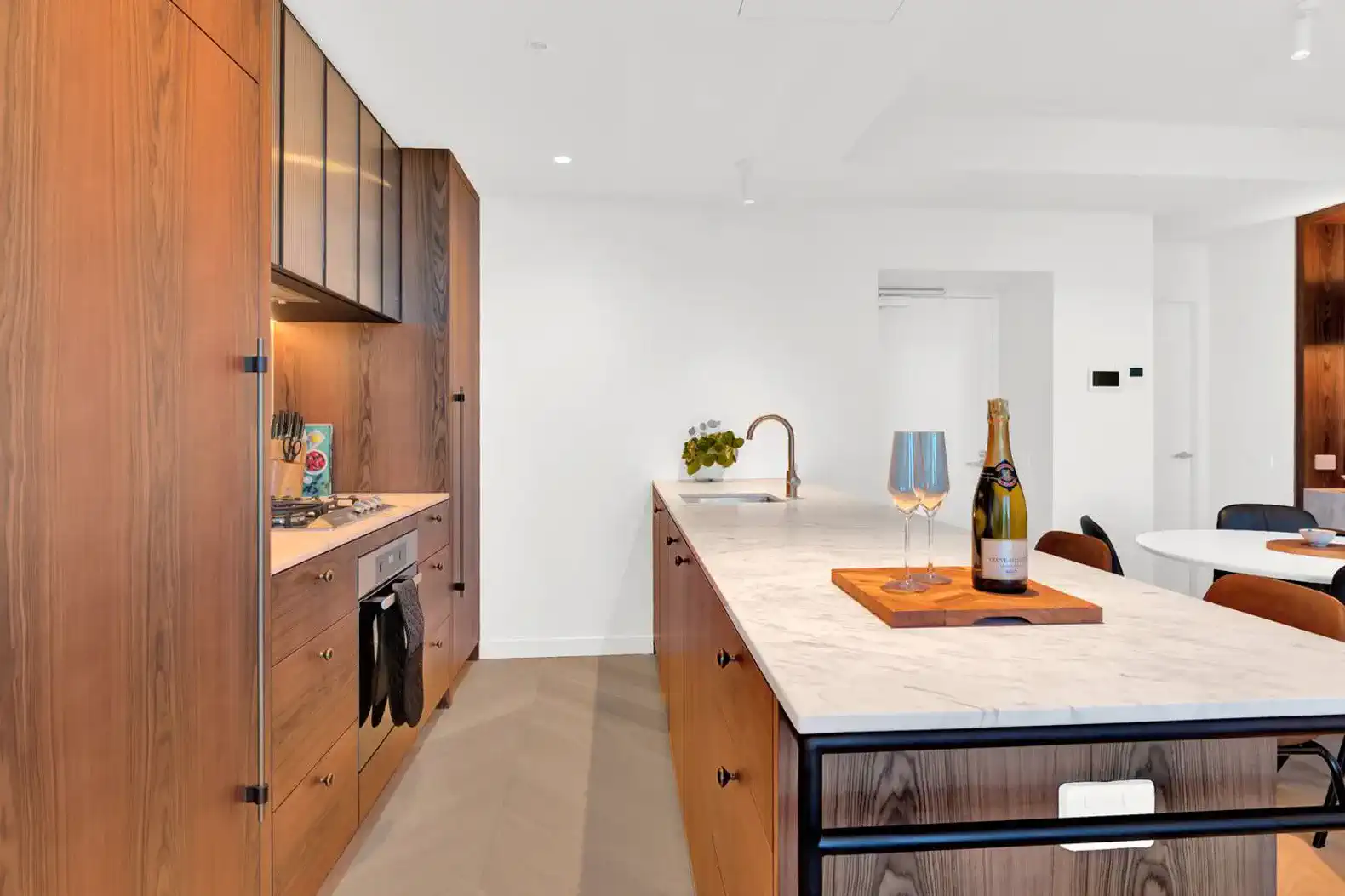 Modern kitchen with wooden cabinetry, marble countertops, and a stylish island