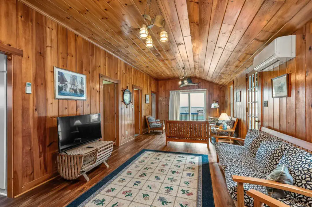 Acogedora sala de estar con paredes de madera, asientos cómodos y grandes ventanales con vista