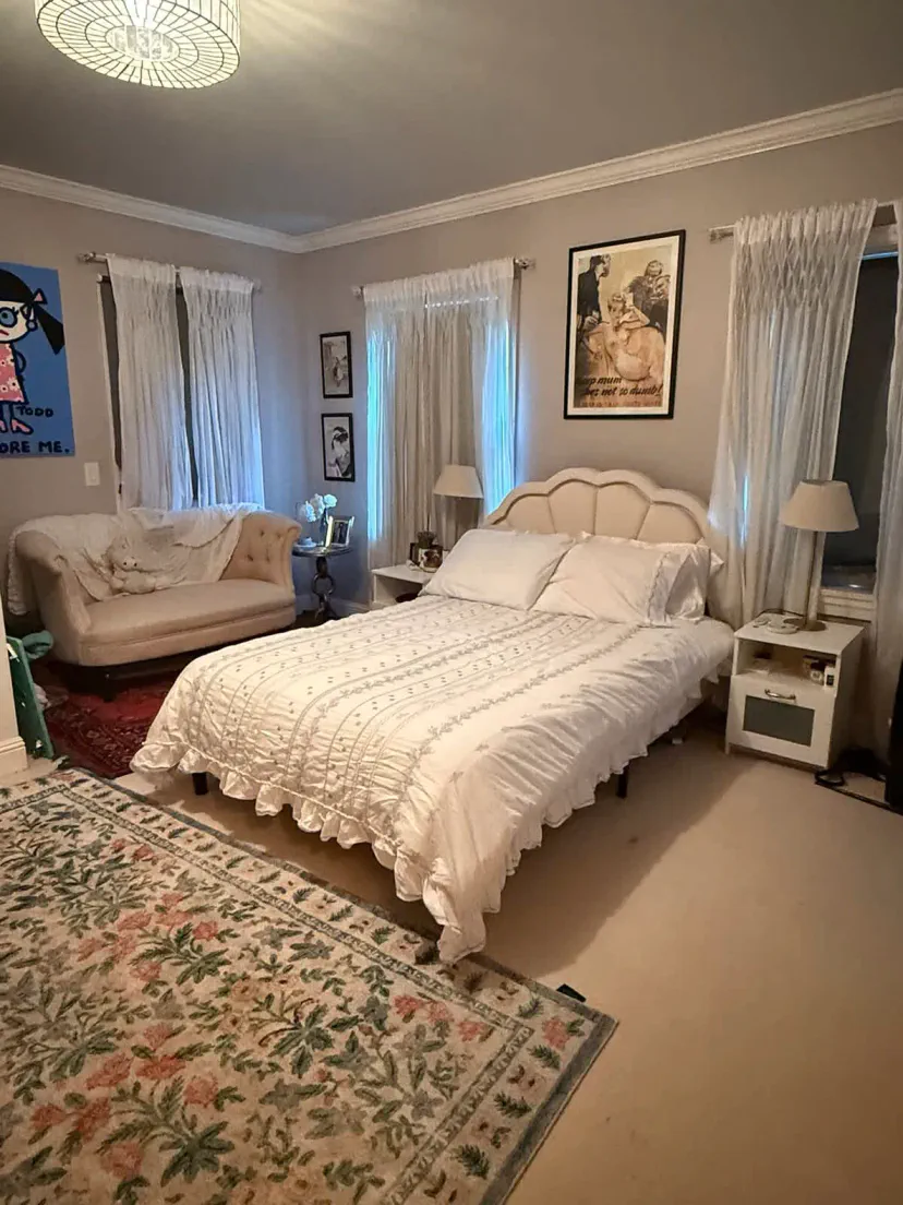 Cozy master bedroom with a white bed, plush seating area, and decorative rugs