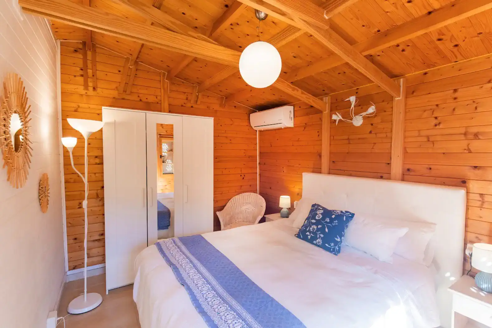 Cozy bedroom with wooden walls, air conditioning, and a comfortable bed