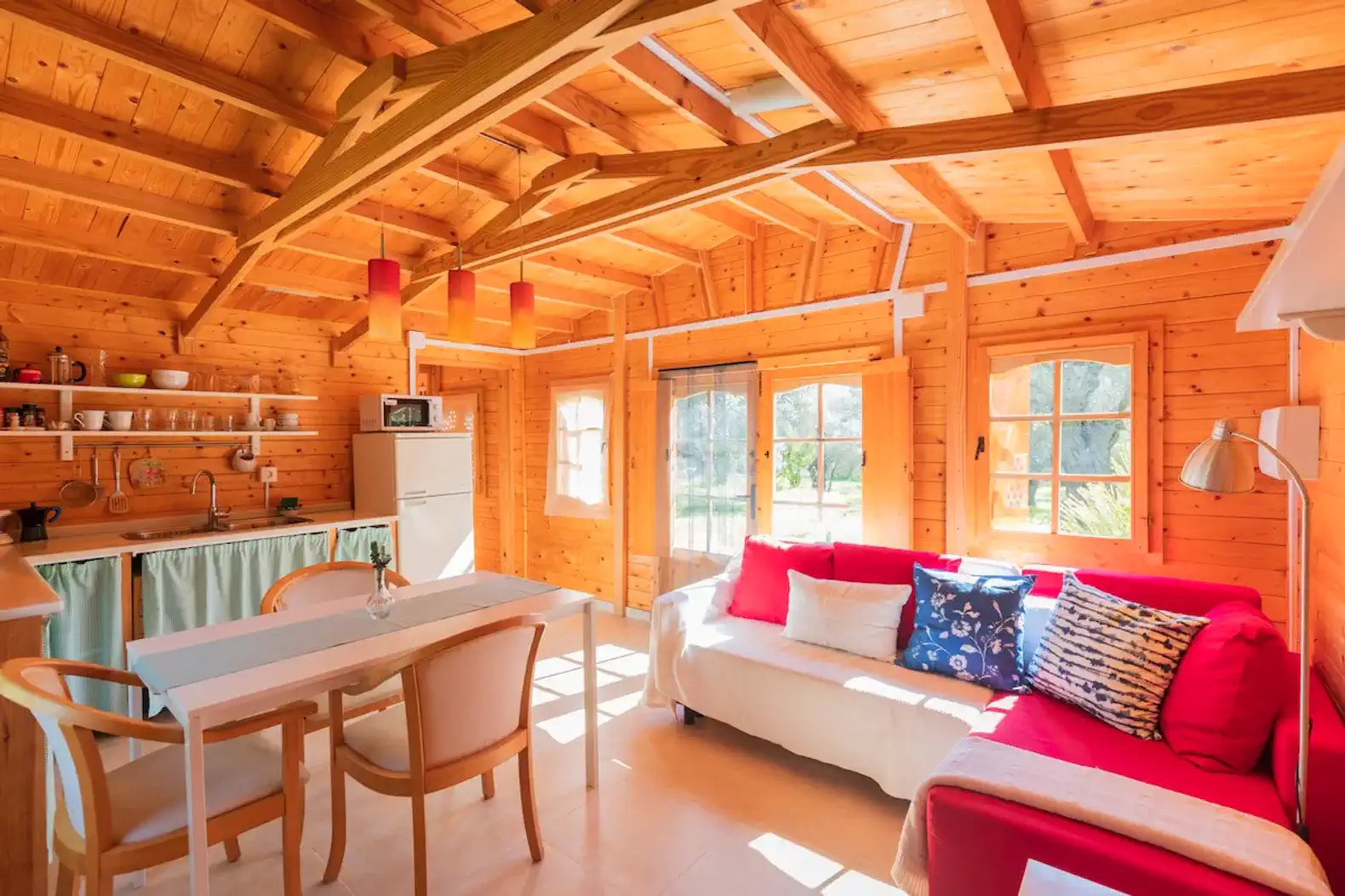 Cozy wooden living area with kitchen, dining table, and bright seating