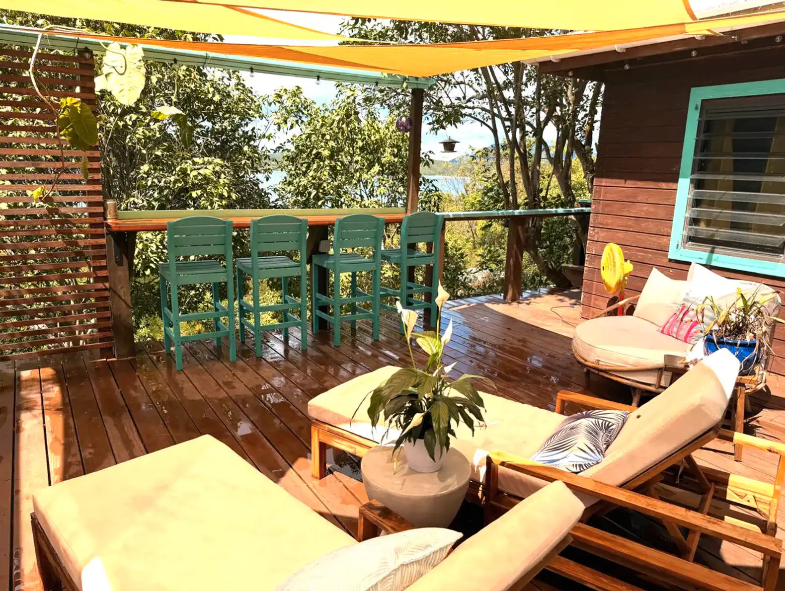 Spacious outdoor deck with lounge chairs and bar seating surrounded by lush greenery