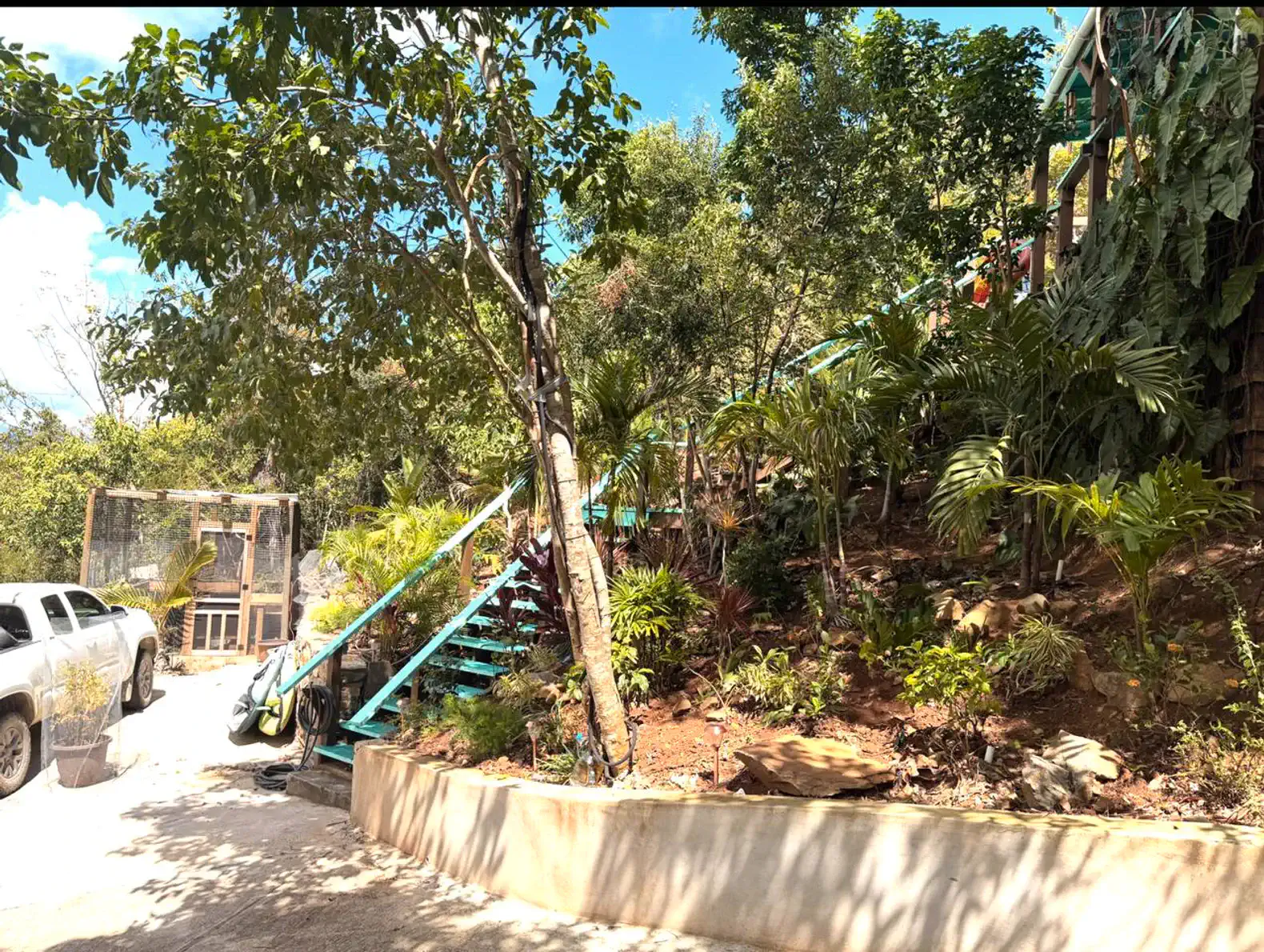 Lush greenery and stairs leading up to the villa with a vehicle parked nearby
