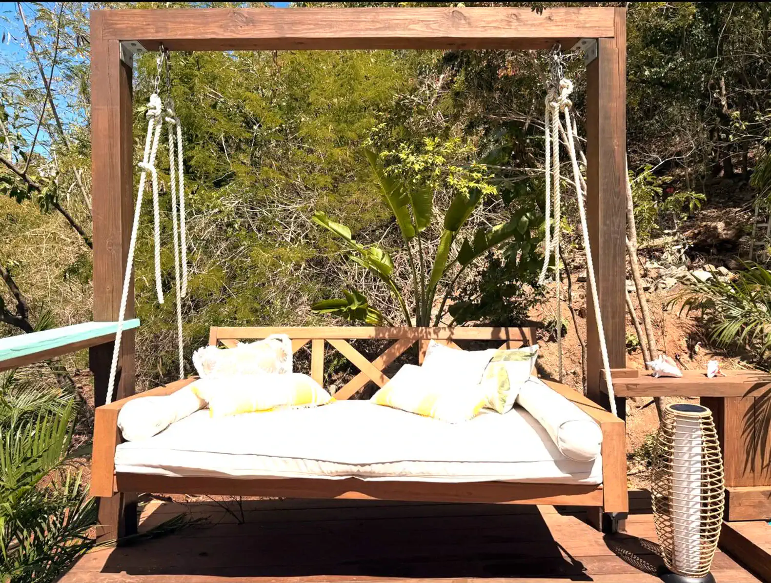 Cozy outdoor swing bed with cushions surrounded by lush greenery