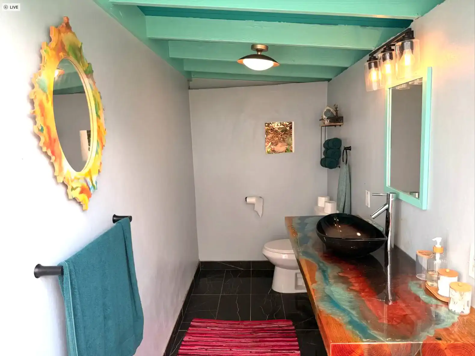 Stylish bathroom with a unique sink, colorful mirror, and modern fixtures